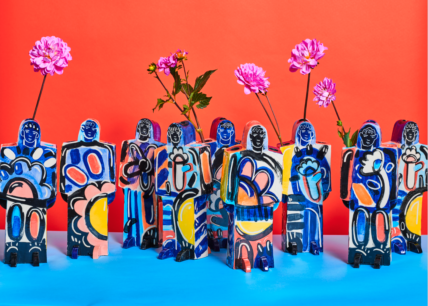 A line up of brightly coloured figures painted with oversized flowers